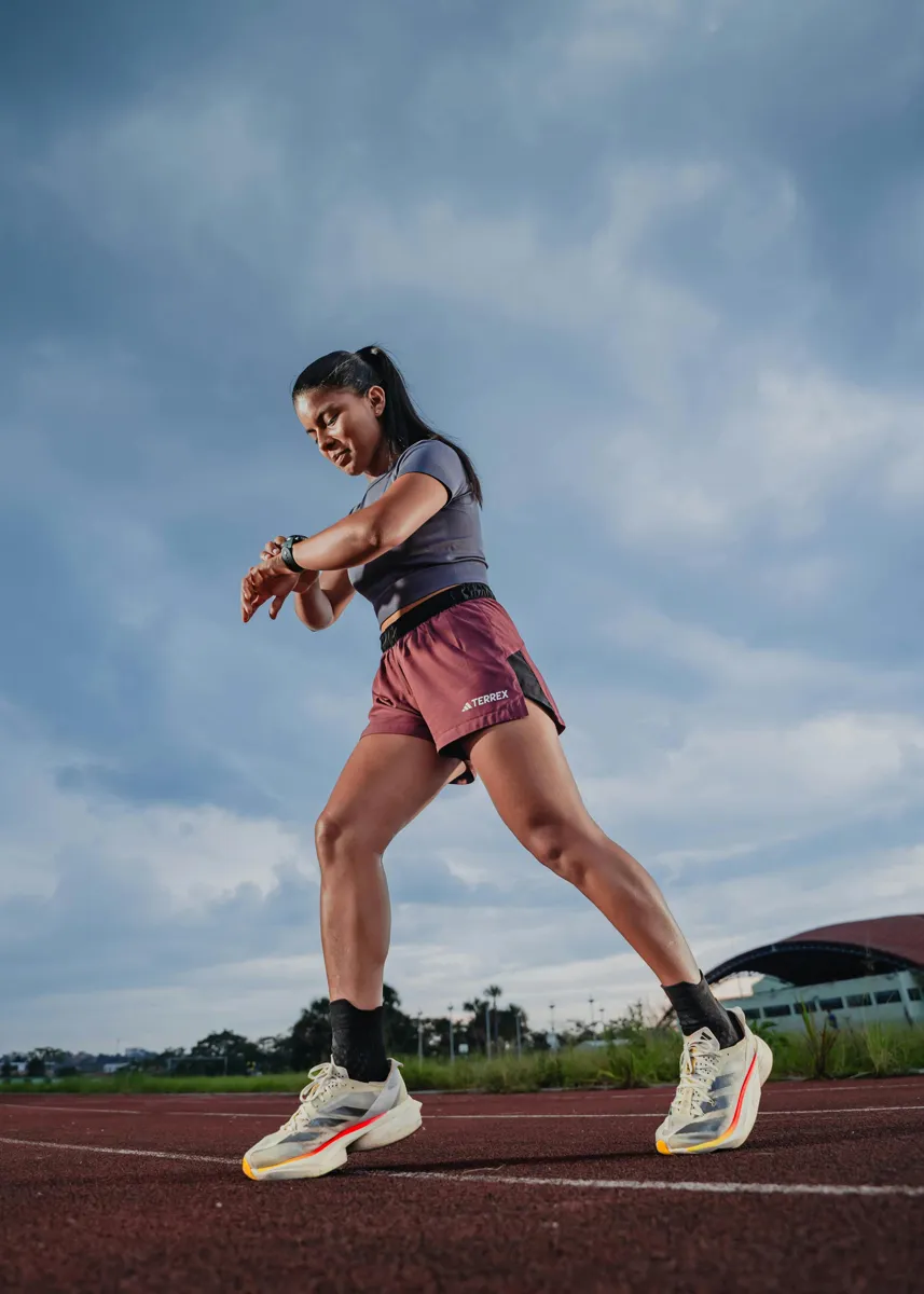 Runner checking a sports watch on an athletics track